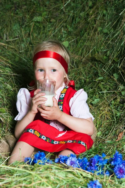 The little girl with a milk glass on hay — Stock Photo, Image