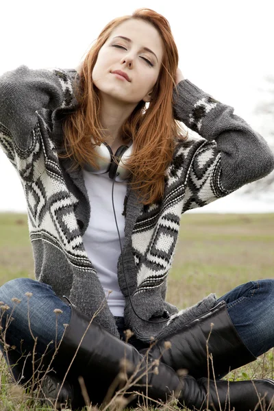 Fată tristă cu căști stând pe pajiște de primăvară . — Fotografie, imagine de stoc
