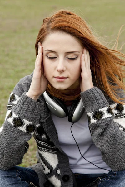 伤心的女孩用耳机坐在春天草甸. — 图库照片