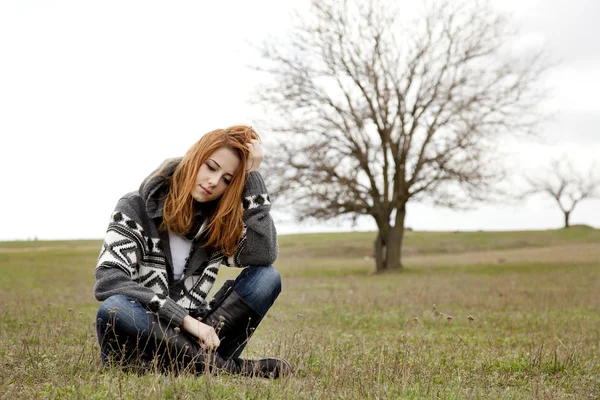 Triste fille avec écouteurs assis à la prairie de printemps . — Photo