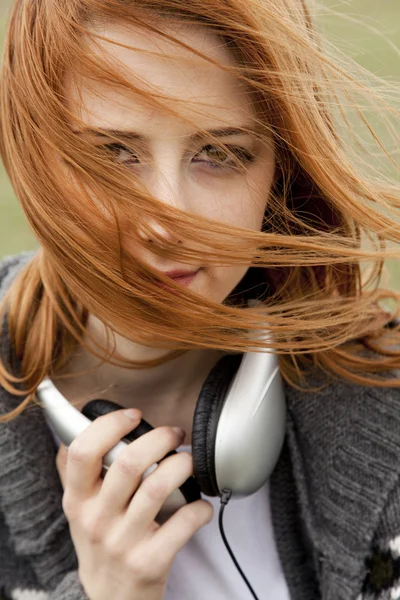 Sad girl with headphones sitting at green spring grass. — Stock Photo, Image
