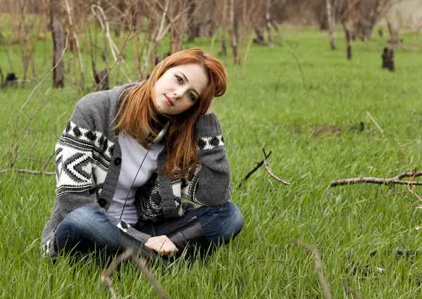 녹색 봄 잔디에 앉아 젊은 패션 소녀. — 스톡 사진