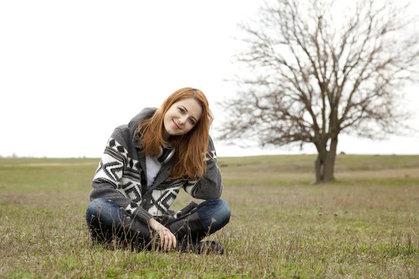 녹색 봄 잔디에 앉아 헤드폰으로 젊은 패션 소녀 — 스톡 사진