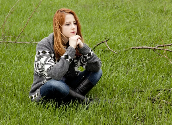Jonge mode meisje zit op groene lente gras. — Stockfoto