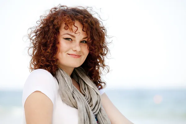 Grappig tiener meisje, zittend op het zand op het strand. — Stockfoto