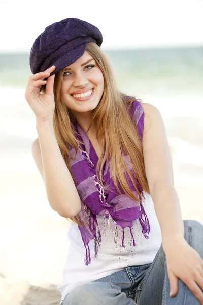 Grappig tiener meisje, zittend op het zand op het strand. — Stockfoto