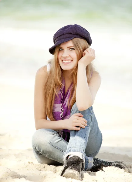 Zabawna dziewczyna siedzi na piasku na plaży. — Zdjęcie stockowe