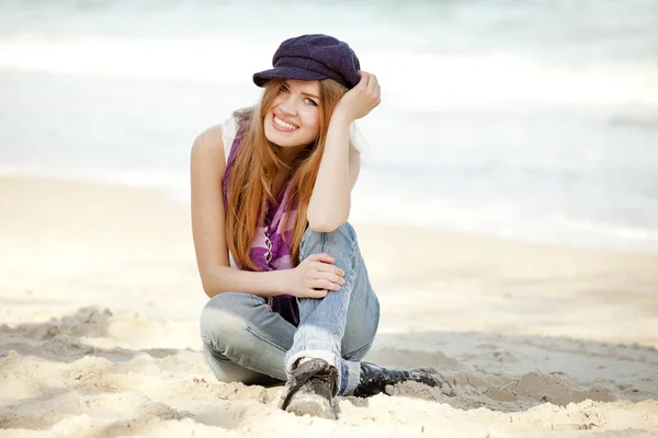 Kum plaj üzerinde oturan genç kız. — Stok fotoğraf
