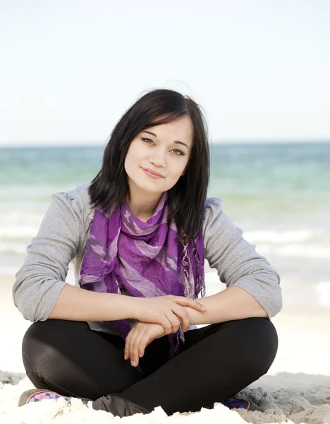 Kum plaj üzerinde oturan genç kız. — Stok fotoğraf