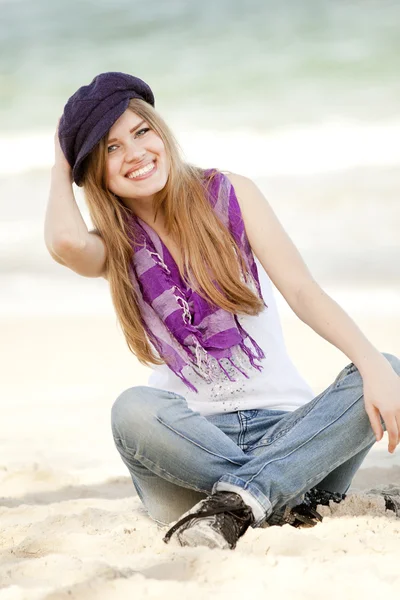 Zabawna dziewczyna siedzi na piasku na plaży. — Zdjęcie stockowe