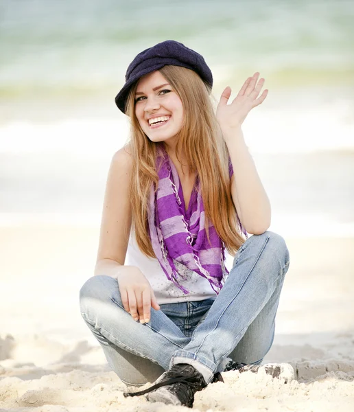 Grappig tiener meisje, zittend op het zand op het strand. — Stockfoto