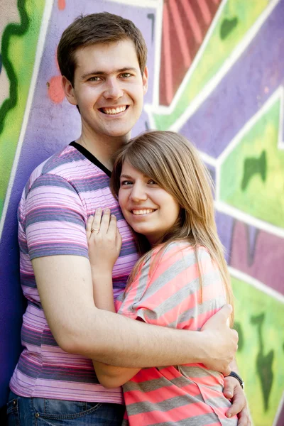 Νεαρό ζευγάρι κοντά γκράφιτι φόντο. — Φωτογραφία Αρχείου