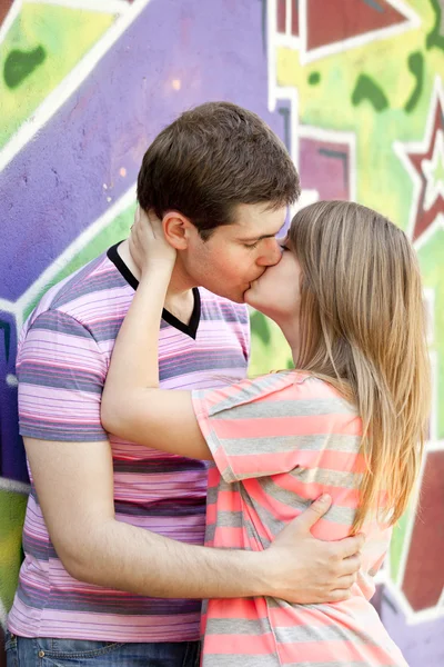 Ungt par kyssas nära graffiti bakgrund. — Stockfoto