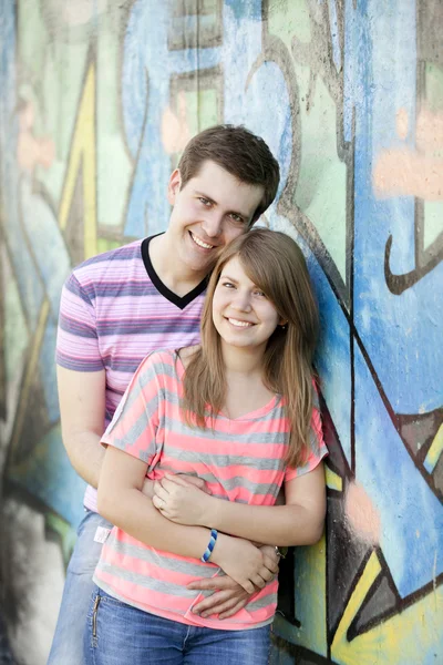 Mladý pár poblíž graffiti pozadí. — Stock fotografie