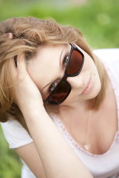 Блондинка в сонцезахисних окулярах в літньому парку . — стокове фото