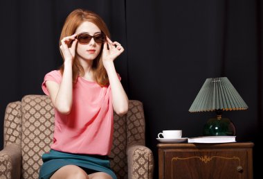 Redhead girl in armchair. 70s