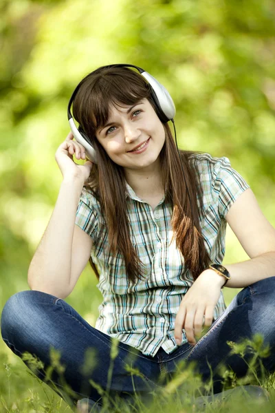 Chica de la moda joven con auriculares en la hierba verde primavera . — Foto de Stock