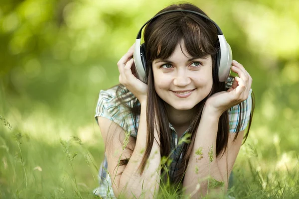 Νεαρό κορίτσι της μόδας με ακουστικά στο πράσινο γρασίδι άνοιξη. — Φωτογραφία Αρχείου