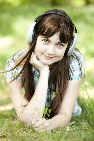 年轻时尚女郎，头戴耳机，绿色春草. — 图库照片