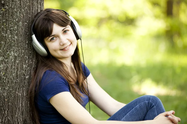 Ung mode flicka med hörlurar på grön vår gräs. — Stockfoto