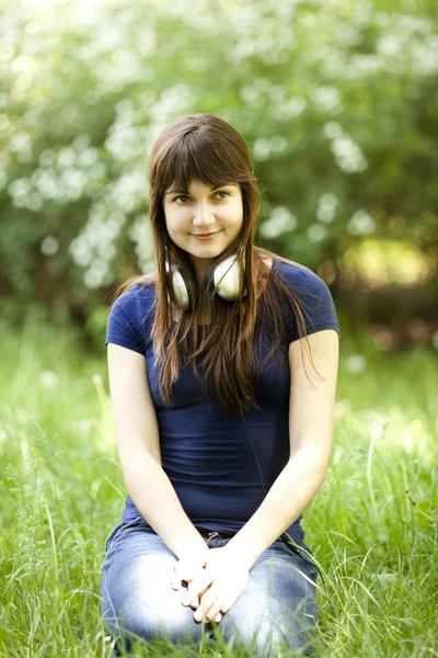 Giovane ragazza di moda con le cuffie a erba verde primavera . — Foto Stock