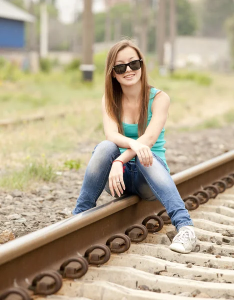 Νεαρό κορίτσι με τα γυαλιά που κάθεται στο σιδηροδρομικό. — Φωτογραφία Αρχείου