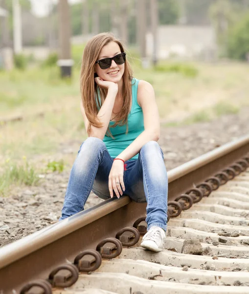 Junges Mädchen mit Brille sitzt am Bahnhof. — Stockfoto