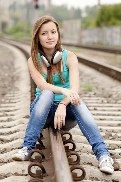 Chica adolescente con auriculares en los ferrocarriles . — Foto de Stock