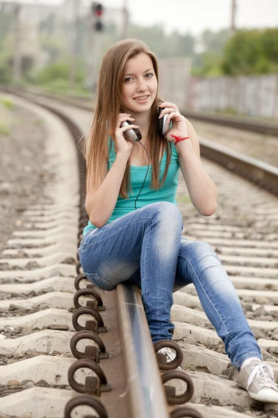 十几岁的女孩用耳机在铁路. — 图库照片