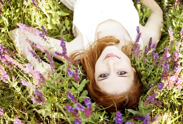 Rusovláska dívka v purpurové květy. — Stock fotografie