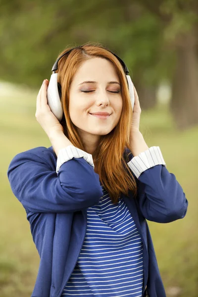 Jonge mode meisje met koptelefoon op lente buiten. — Stockfoto