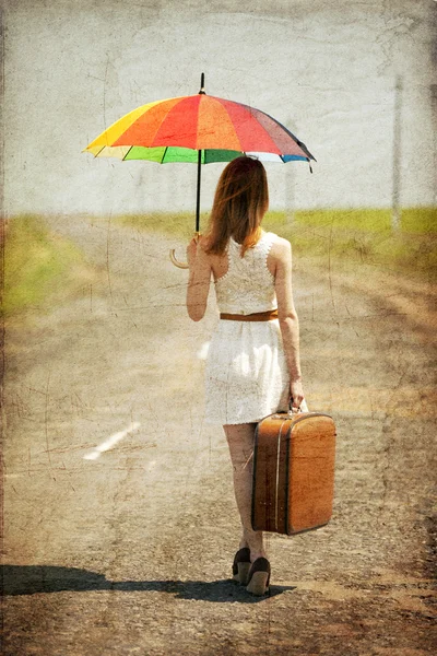 Einsames Mädchen mit Koffer und Regenschirm an Landstraße. — Stockfoto