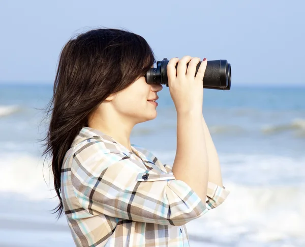 Dívka s binokulární na pláži. — Stock fotografie