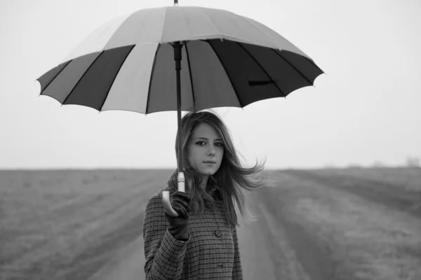 Eenzaam meisje met paraplu op landweg. — Stockfoto