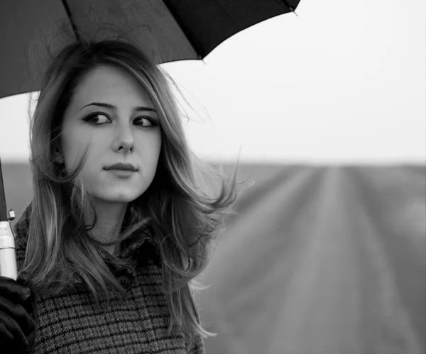 Eenzaam meisje met paraplu op landweg. — Stockfoto