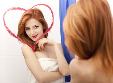 Kızıl saçlı kız banyoda kalbinde olan ayna yakınındaki.