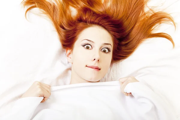 Menina de cabelos vermelhos surpreso na cama. Estúdio . — Fotografia de Stock