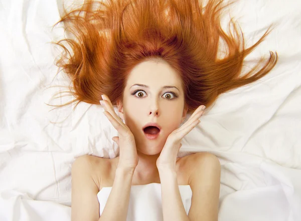 Überrascht rothaarige Mädchen im Bett. Studioaufnahme. — Stockfoto