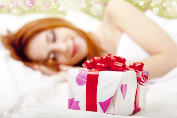 Red-haired girl in bed with gift — Stock Photo, Image