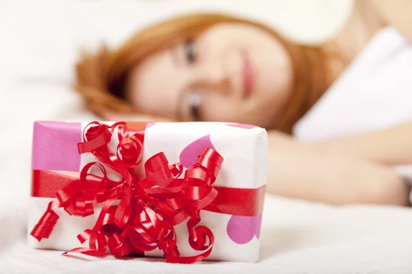 Red-haired girl in bed with gift — Stock Photo, Image