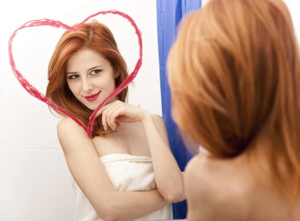 Pelirroja chica cerca del espejo con el corazón en él en el baño . — Foto de Stock