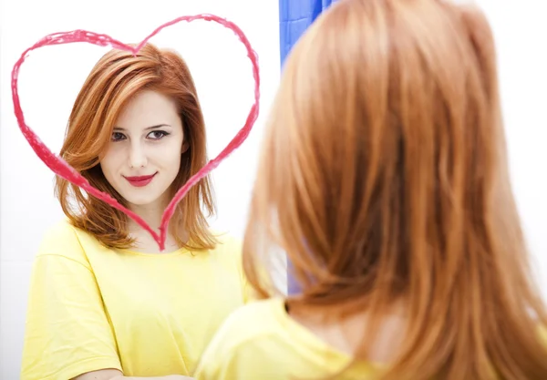 Κοκκινομάλλα κοπέλα κοντά καθρέφτη με την καρδιά σε αυτό στο μπάνιο. — Φωτογραφία Αρχείου