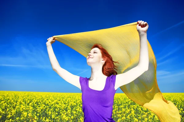 Young woman with open arms keep yellow silk on wind at rapeseed — Stock Photo, Image