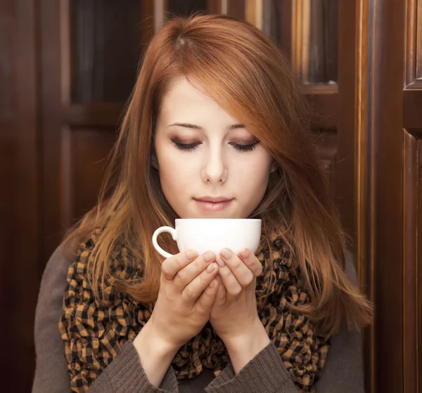 Style rousse fille boire du café près des portes en bois . — Photo