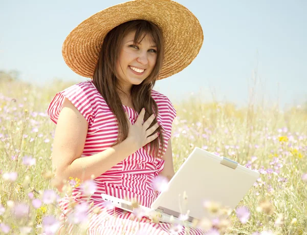 Beautiful brunette girl in hat at the park with computer. — Stock Photo, Image