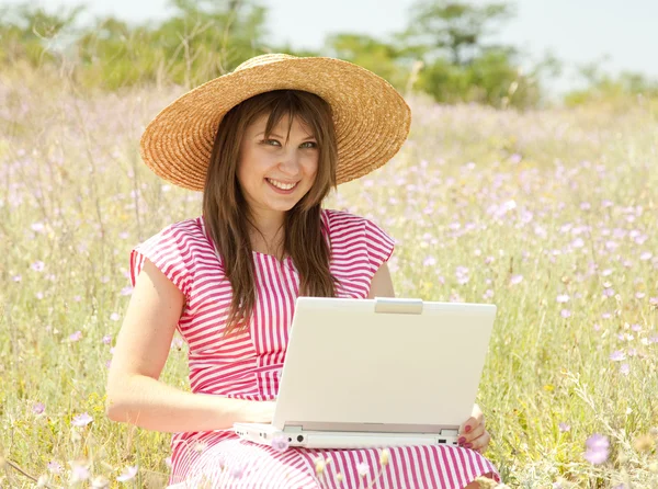 Piękna brunetka dziewczyna w kapeluszu w parku z komputera. — Zdjęcie stockowe