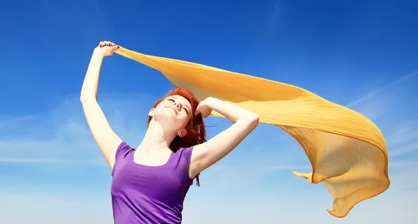 Молодая женщина с распростертыми объятьями держит желтый шелк на ветру — стоковое фото