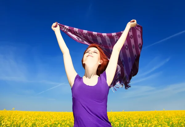 Young woman with open arms keep yellow silk on wind at rapeseed — Stock Photo, Image