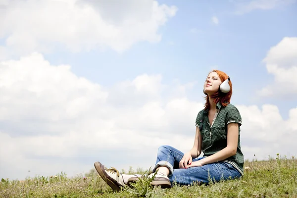 Jonge mode meisje met koptelefoon op gras in de buurt van lake in het voorjaar van — Stockfoto