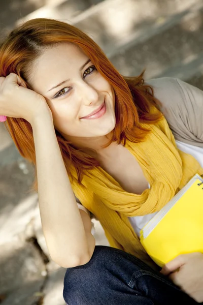 Red-haired student girl with notebook sitting at outdoor. — Stock Photo, Image